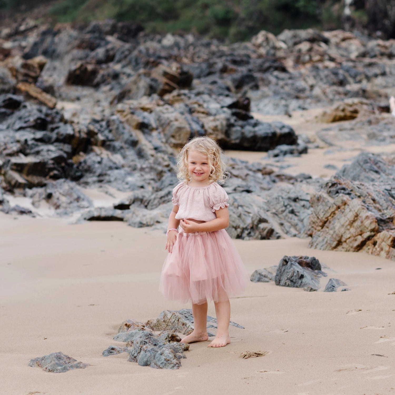 Picture of a girl on a beach in a pink tulle ballerina skirt and pink ruffle top